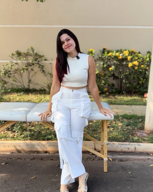 Yasmin de roupa branca apoiada em uma maca, ao ar livre